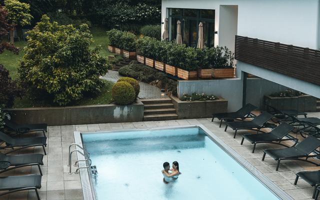 ein pärchen schwimmt im aussenpool im hotelgarten bei regen im vulkanlandhotel legenstein in bad gleichenberg